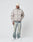 A man wears the LIVE FAST DIE YOUNG LFDY Puffer Jacket in beige, styled with light wash jeans, white sneakers, and a cream knit beanie, standing against a plain white background and looking to his left with hands in pockets.