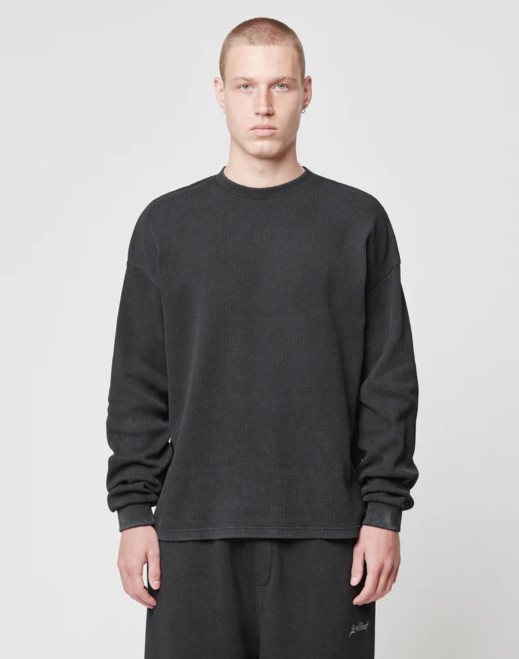 A person with short hair stands facing forward, wearing a loose-fitting LIVE FAST DIE YOUNG Blank Waffle Longsleeve and matching black pants, both in an Oversize Fit made from 100% cotton, against a plain white background.