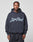 A man stands facing the camera in a dark blue LFDY Script Hooded sweatshirt from LIVE FAST DIE YOUNG, featuring “LivePart” in large script on the front. The oversized fit adds comfort and style against a light gray background.