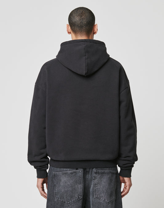 A person with short hair is seen from behind wearing the LIVE FAST DIE YOUNG LFDY The Bulldog Hooded and loose-fitting dark denim jeans, standing against a plain light gray background.