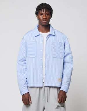 A man with short, styled hair and a neutral expression wears the LIVE FAST DIE YOUNG LFDY Striped Padded Shirt over a white t-shirt and gray sweatpants, standing against a plain background.