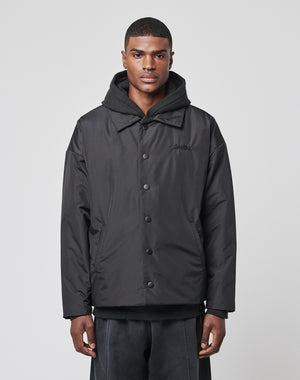 A man faces forward against a plain light gray background, wearing the LIVE FAST DIE YOUNG Collar Winter Jacket—a black button-up with subtle logo-stitch detail—over an oversized black hooded sweatshirt.