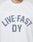 A person wears the LFDY Boxy Jersey by LIVE FAST DIE YOUNG, a boxy fit white mesh top with blue polka-dot front print letters. Only the neck and upper chest are visible.