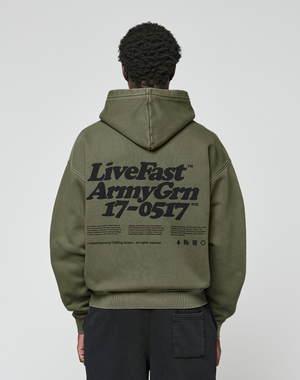 A person seen from the back wears the LIVE FAST DIE YOUNG Basic 360 Hooded in olive green, featuring oversize fit, large black “LiveFast Army Grn 17-0517” text, smaller details and visible topstitching.