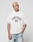 A person with short bleached blond hair wears the LFDY Boxy Jersey from LIVE FAST DIE YOUNG and light blue jeans, standing against a plain light gray background with a neutral expression.