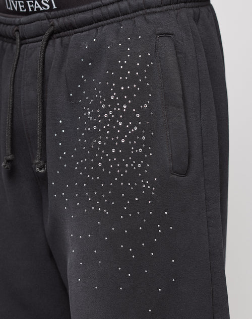 The Live Fast Rhinestone Jogger by LIVE FAST DIE YOUNG features black sweatpants with an elastic waistband, side pocket, rhinestone Muster on the upper thigh, partially visible "LIVE FAST" text, and a wide fit for comfort.
