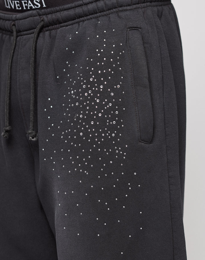 The Live Fast Rhinestone Jogger by LIVE FAST DIE YOUNG features black sweatpants with an elastic waistband, side pocket, rhinestone Muster on the upper thigh, partially visible "LIVE FAST" text, and a wide fit for comfort.