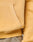 Close-up of a person wearing the LIVE FAST DIE YOUNG LFDY Corp. Hooded sweatshirt in light yellow, oversized fit with a front pocket and ribbed hem, paired with khaki pants. Only part of the arm, pocket, and waistband are visible.