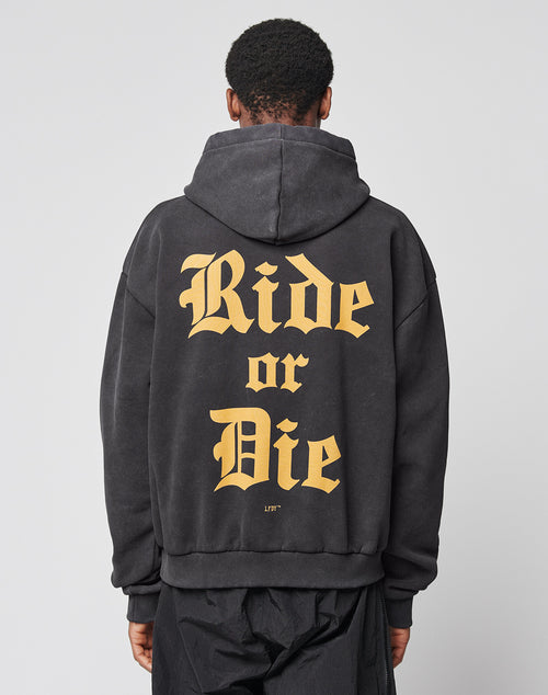 A person wearing the LIVE FAST DIE YOUNG Ride or Die Hooded, an oversize black sweatshirt with bold yellow Ride or Die text on the back, doppellagige Kapuze, and a soft Baumwolle-Polyester blend, faces away against a plain background.