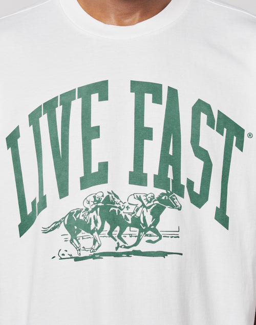 The Live Fast Stallion Tee by LIVE FAST DIE YOUNG is a white, oversized cotton T-shirt with a bold front print: large green LIVE FAST text above an illustration of two jockeys racing horses.