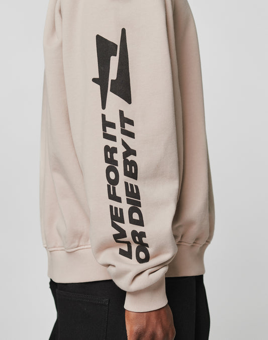 A person wearing the LIVE FAST DIE YOUNG Live For It Sweater in beige, featuring bold black LIVE FOR IT OR DIE BY IT text and a lightning bolt on the sleeve. Made from 100% Baumwolle for superior comfort.