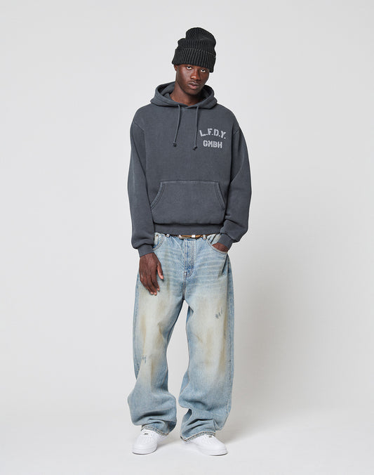 A person wears a black knit beanie, a dark gray LIVE FAST DIE YOUNG hoodie, LFDY Baggy Dirt Denim jeans, a white belt, and white sneakers while standing against a plain light background.