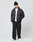 A person in a black LIVE FAST DIE YOUNG LFDY Puffer Jacket with front logo stitching, black beanie, white tee, loose black pants, and white sneakers stands against a plain white background with hands in jacket pockets.