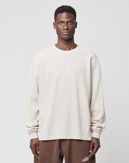 A man faces forward against a plain background, wearing the LIVE FAST DIE YOUNG Basic Waffle Longsleeve in an oversize fit and brown sweatpants.