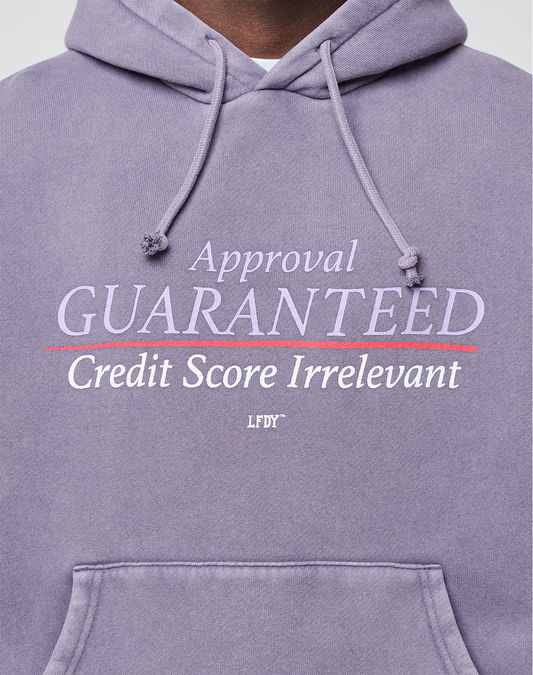 A person wears an oversize fit LFDY Hotline Hooded in purple by LIVE FAST DIE YOUNG, featuring “Approval GUARANTEED Credit Score Irrelevant” prints front and back and a drawstring hood for added comfort and style.