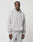 A man wears the LIVE FAST DIE YOUNG Basic Blank Hooded, a light gray oversize-fit hoodie with front pocket and matching sweatpants, made from soft cotton and polyester, standing against a white background with a neutral expression.