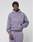 A young man wears a lavender LFDY Hotline Hooded by LIVE FAST DIE YOUNG with front and back print, featuring “Approval GUARANTEED Credit Score Irrelevant” and matching sweatpants, standing neutrally against a plain background.