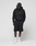 A person wears a black oversize fit Basic Livefast Hooded by LIVE FAST DIE YOUNG, paired with black shorts, black cap, white socks, and white sneakers. They stand against a plain light background, looking down with hands in pockets.