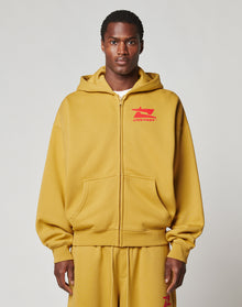 A man faces forward against a light gray background, wearing the LIVE FAST DIE YOUNG Live Fast Sweatsuit Jacket in mustard yellow with a bold LIVE FAST front print and red chest graphic, paired with matching oversized sweatpants. | model