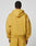 A person with short hair is seen from behind wearing the LIVE FAST DIE YOUNG Live Fast Sweatsuit Jacket in mustard yellow, featuring an oversized fit, large hood, and dropped shoulders. The background is plain and light-colored.