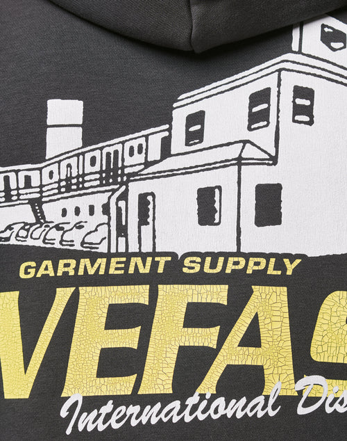 Close-up of the LFDY Supply Hooded by LIVE FAST DIE YOUNG—a black, oversized hoodie with a discharge print of white buildings, yellow cracked VEFAS text, smaller GARMENT SUPPLY International Dis. details, in soft Baumwolle Polyester blend.