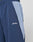 Close-up of a person wearing LIVE FAST DIE YOUNG Basic Nylon Trackpants, navy blue with elastic waistband, light blue and white pocket trim, zippered pockets, and the Live Fast logo embroidered near the pocket.