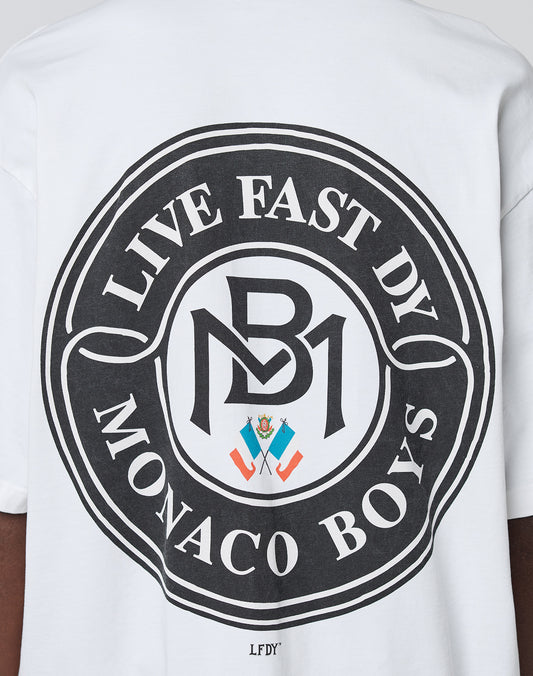 The LFDY Monaco Boys Tee by LIVE FAST DIE YOUNG features a large circular black graphic, LIVE FAST DY MONACO BOYS, bold MB logo, and colorful crest on the back. Made from 100% Baumwolle in an Oversize Fit for comfort and style.