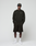 A man faces forward in a LIVE FAST DIE YOUNG Basic +49 Chest Sweater, black shorts, a black cap with yellow lettering, white socks, and white sneakers, set against a plain light background.