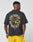 A person wears the LFDY Circle Dog Tee by LIVE FAST DIE YOUNG—an oversized black T-shirt featuring a large snarling dog graphic and Live Fast Die, Beware of Dogs text on the back—paired with bright yellow shorts.