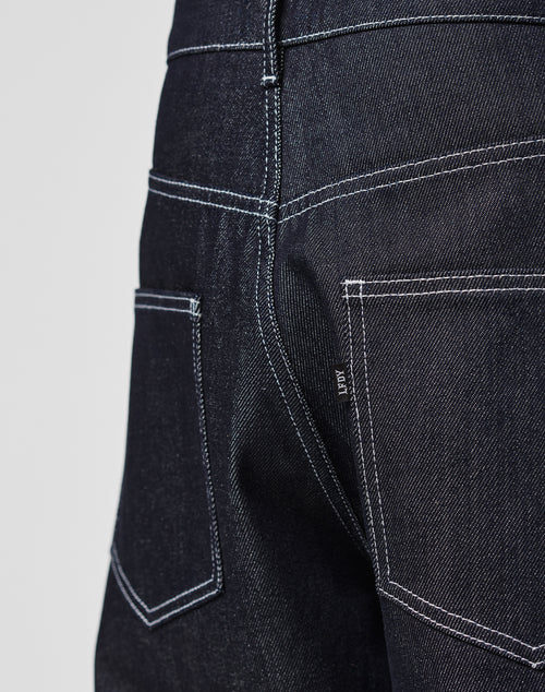 Close-up of the back of LFDY Baggy Denim jeans in dark blue 100% cotton, featuring a baggy fit in raw denim, two back pockets with white stitching, and a small fabric tag on the right pocket seam.