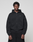 A young man stands against a plain background, wearing the LIVE FAST DIE YOUNG Basic Evidence Hooded Zip in black with subtle branding on the left chest and matching black pants. His hands are by his sides as he looks straight at the camera.