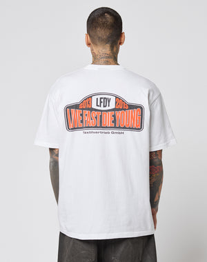 A tattooed individual wears the Live Fast 2013 Tee by LIVE FAST DIE YOUNG, a white Regular Fit t-shirt made of 100% cotton, featuring bold back prints and clean topstitching.