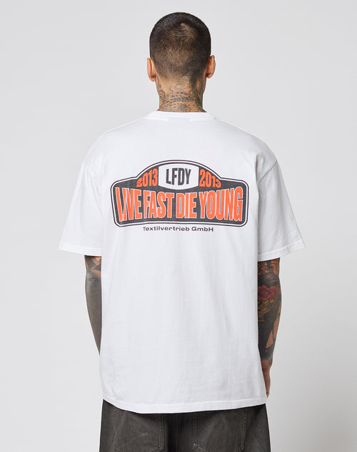 A tattooed individual wears the Live Fast 2013 Tee by LIVE FAST DIE YOUNG, a white Regular Fit t-shirt made of 100% cotton, featuring bold back prints and clean topstitching.