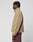 A person with short dreadlocks stands in profile, wearing the beige LFDY Teddy Jacket from LIVE FAST DIE YOUNG with maroon oversize-fit pants, set against a plain white background.