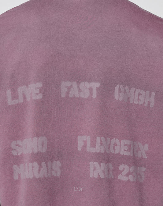 The Live Fast District Tee by LIVE FAST DIE YOUNG is an oversized mauve shirt with white stenciled text: LIVE FAST GMBH, SOHO, FLINGER, MARAIS, INC. 2355. Made from 100% Baumwolle, the fabric looks soft on a plain background.