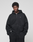 A person wears the Basic Evidence Hooded Zip by LIVE FAST DIE YOUNG, featuring subtle distressing and branding, paired with oversized black pants. They stand against a light gray background, looking at the camera with hands in their pockets.