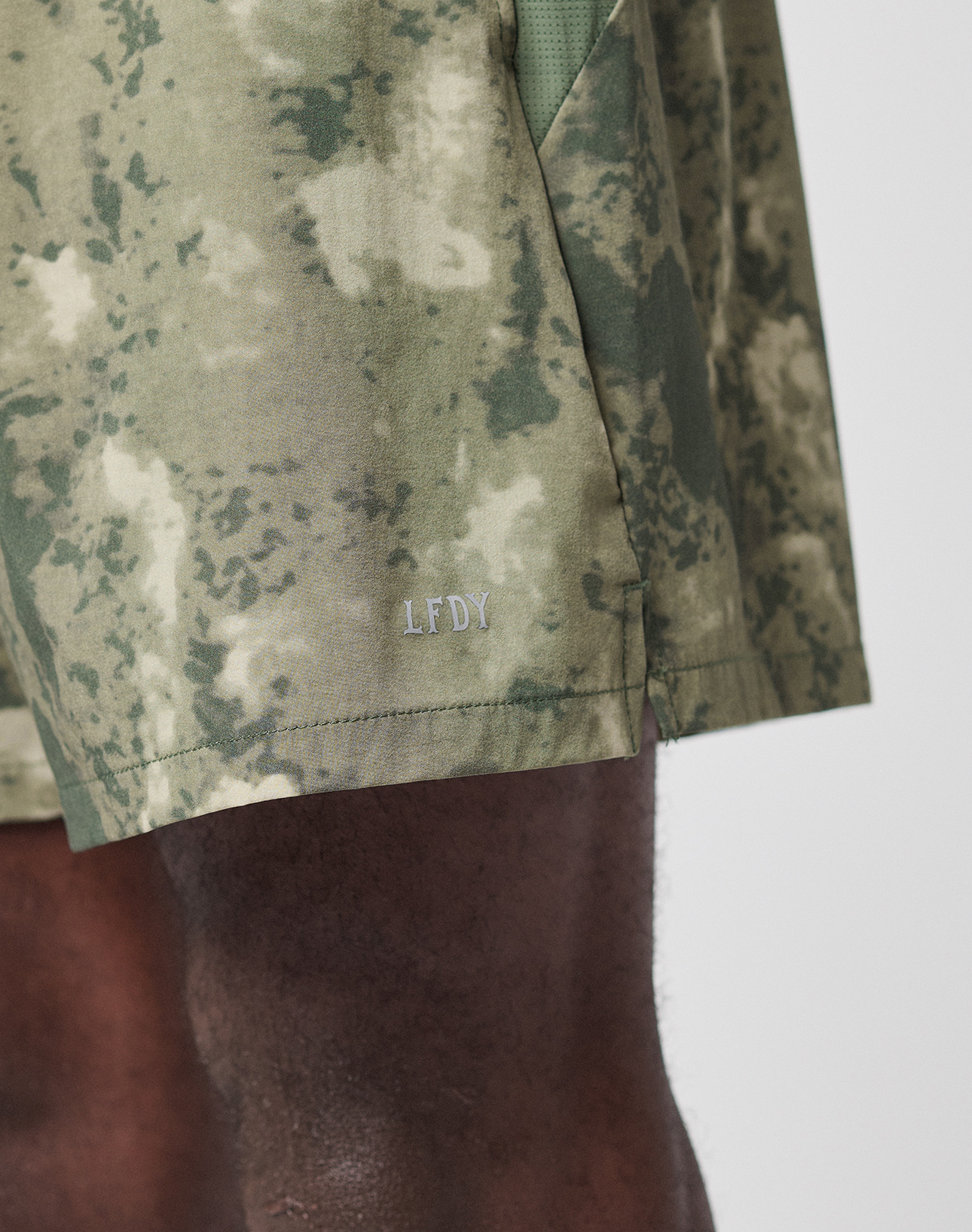 A close-up of the LFDY Performance Running Shorts by LIVE FAST DIE YOUNG, featuring integrated tights and a reflective logo print.