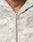 Close-up of a person wearing the Live Fast Canvas Jacket by LIVE FAST DIE YOUNG, featuring a light gray, textured marbled pattern, metal zipper pulled up most of the way, and an oversize fit showing the upper chest and neck.