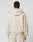 A person in an oversize fit, light beige LFDY Pleated Hooded Zip by LIVE FAST DIE YOUNG with Kapuze mit Kordel and matching sweatpants, made from soft Baumwolle, stands facing away against a plain light gray background.