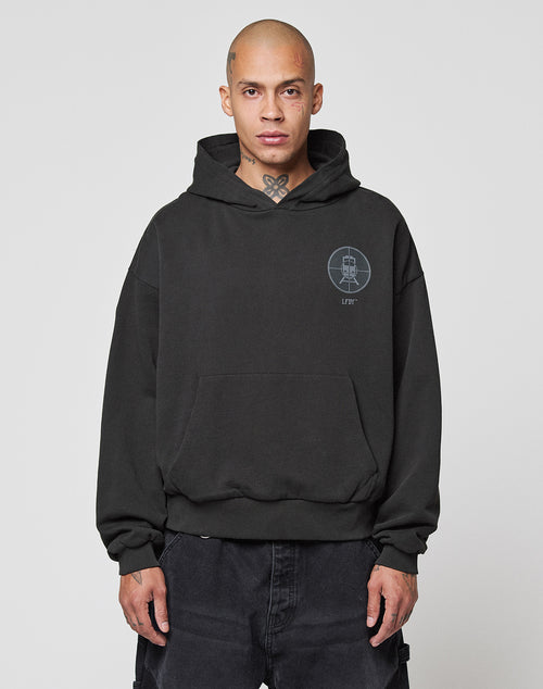 A person with a shaved head wears the LFDY Vandals Hooded by LIVE FAST DIE YOUNG, made from 100% cotton, paired with black pants. The oversize hoodie features a double-layered hood and a small logo on the left chest, set against a white background.