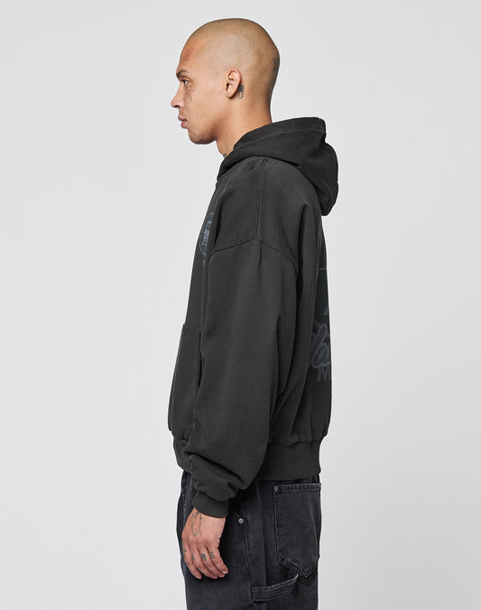 A person with a shaved head, visible tattoos, and a black LFDY Vandals Hooded by LIVE FAST DIE YOUNG made from 100% Baumwolle stands in profile against a plain white background.