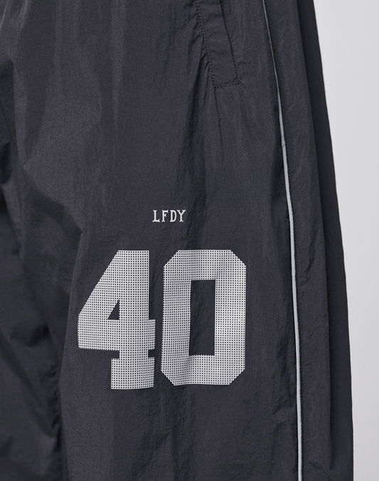 The LFDY Performance Trackpants by LIVE FAST DIE YOUNG feature black nylon fabric, white piping, and a reflective print. A white number 40 with "LFDY" above it appears on the left thigh for standout style.
