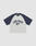 The Live Fast Raglan Tee by LIVE FAST DIE YOUNG features navy Raglan sleeves, a white body, and bold navy "LIVE FAST DY" text on the chest. Made from 100% cotton for comfort.