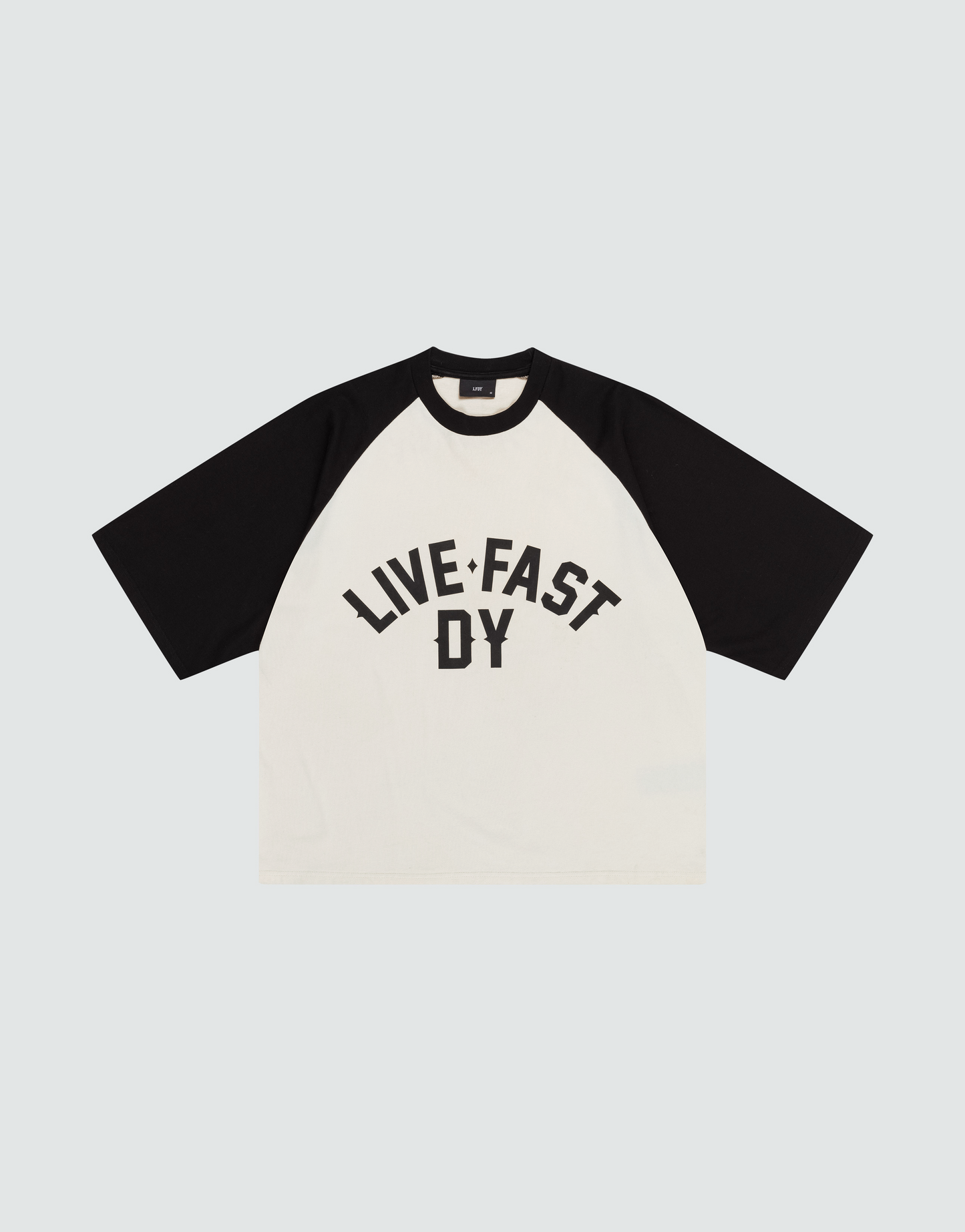The Live Fast Raglan Tee by LIVE FAST DIE YOUNG is a black and white, boxy oversized raglan t-shirt made from 100% cotton, featuring bold "LIVE FAST DY" text on the front in black capital letters.