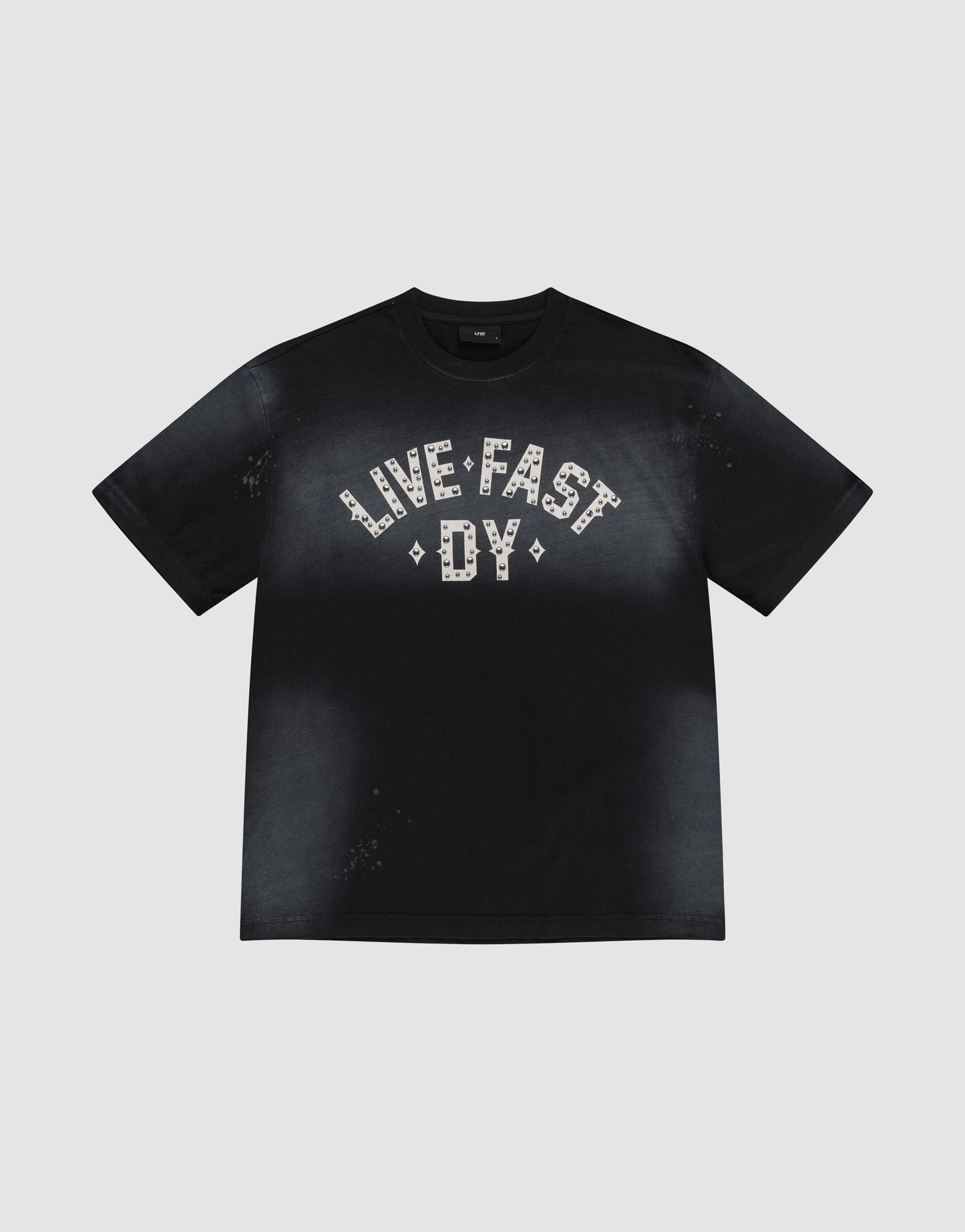 The Live Fast Rivet Tee by LIVE FAST DIE YOUNG is a black 100% Baumwolle shirt with a handgefertigter Sprayeffekt, faded finish, and bold "LIVE FAST DY" in white patterns across the chest. Displayed flat on a light gray background.