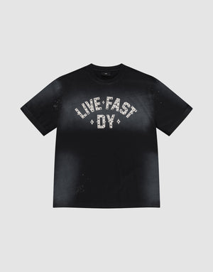 The Live Fast Rivet Tee by LIVE FAST DIE YOUNG is a black 100% Baumwolle shirt with a handgefertigter Sprayeffekt, faded finish, and bold "LIVE FAST DY" in white patterns across the chest. Displayed flat on a light gray background. | plain