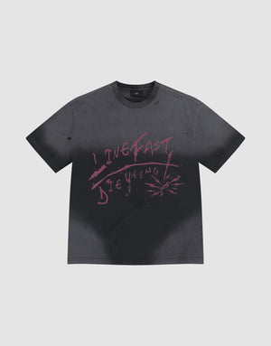 The LFDY Scribble Tee by LIVE FAST DIE YOUNG is a faded black 100% cotton shirt featuring pink graffiti "LIVE FAST DIE YOUNG" text and handmade spray-effect splatters around the lettering. | plain