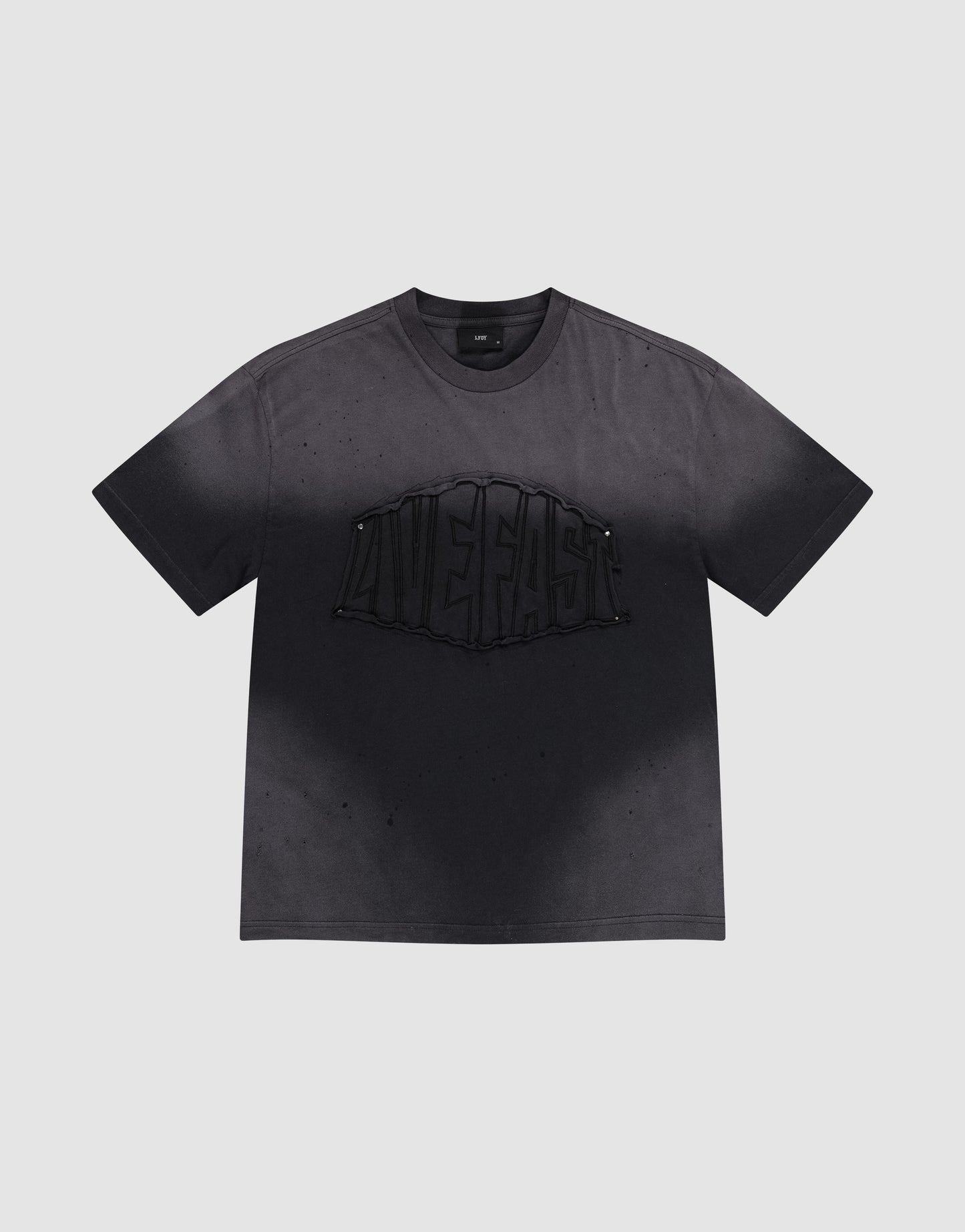 The LFDY Emblem Patch Tee by LIVE FAST DIE YOUNG is a black oversized jersey T-shirt made from 100% cotton, featuring a bold raised 'LIVE FAST' graphic, distressed look with subtle speckles, and a signature logo patch.