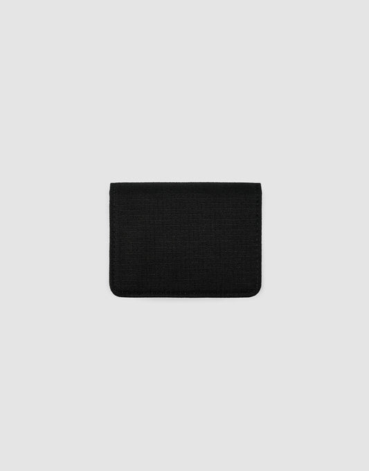 The LFDY Cardholder by LIVE FAST DIE YOUNG, a small rectangular black fabric wallet with Druckknopf-Verschluss, is centered on a plain light gray background, closed to display its minimalist design.