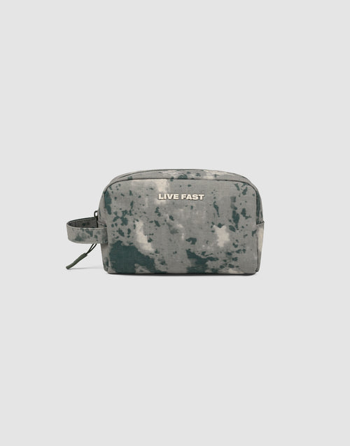 The LFDY Amenity Kit by LIVE FAST DIE YOUNG is a rectangular, tie-dye toiletry bag made from 100% polyester, featuring a large zip compartment, side handle, and "LIVE FAST" in white on the front, set on a plain light gray background.